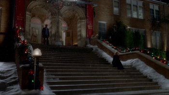 Movie still from “Surviving Christmas” (2004), directed by Mike Mitchell – A person sitting on the steps of a building at night; Extreme Wide shot, High angle
