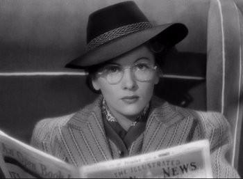 Movie still from “Suspicion” (1941), directed by Alfred Hitchcock – A woman wearing a hat and reading a newspaper; Close Up shot, Low angle