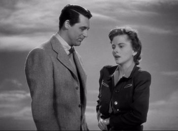 Movie still from “Suspicion” (1941), directed by Alfred Hitchcock – A man and a woman standing next to each other in front of a cloudy sky; Medium shot, Low angle