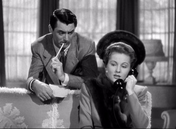 Movie still from “Suspicion” (1941), directed by Alfred Hitchcock – A man and a woman sitting on a couch talking on the phone; Medium shot, High angle