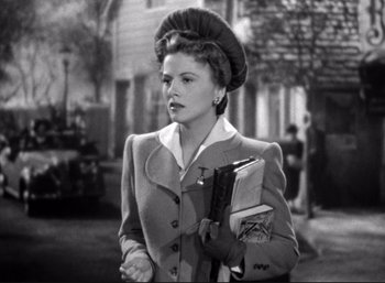 Movie still from “Suspicion” (1941), directed by Alfred Hitchcock – An old photo of a woman in a suit holding a book; Medium shot, Low angle