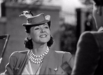 Movie still from “Suspicion” (1941), directed by Alfred Hitchcock – A woman wearing a hat with a bird on top of her head; Close Up shot, Over the shoulder angle