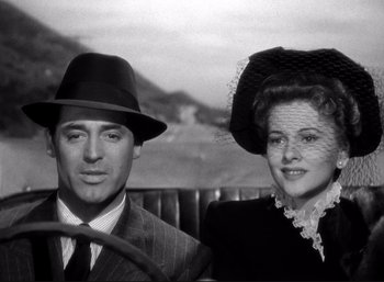 Movie still from “Suspicion” (1941), directed by Alfred Hitchcock – A man and a woman wearing hats and posing for a picture; Close Up shot, Low angle