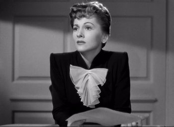 Movie still from “Suspicion” (1941), directed by Alfred Hitchcock – An old black and white photo of a woman wearing a bow tie; Close Up shot, Low angle