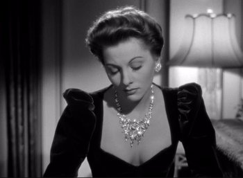Movie still from “Suspicion” (1941), directed by Alfred Hitchcock – An old photo of a woman in a black dress with a diamond necklace; Close Up shot, Low angle