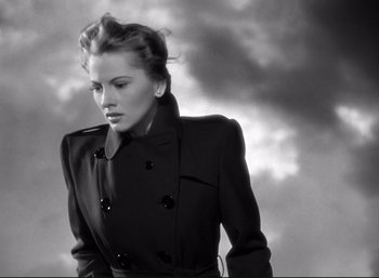 Movie still from “Suspicion” (1941), directed by Alfred Hitchcock – A black and white photo of a woman wearing a coat; Medium shot, Low angle