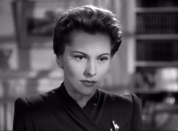 Movie still from “Suspicion” (1941), directed by Alfred Hitchcock – A black and white photo of a woman in a suit; Close Up shot, Over the shoulder angle