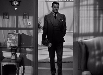 Movie still from “Suspicion” (1941), directed by Alfred Hitchcock – A black and white photo of a man in a suit and tie; Medium shot, Low angle