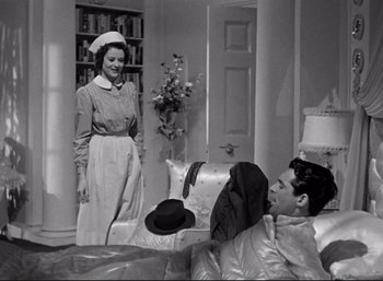 Movie still from “Suspicion” (1941), directed by Alfred Hitchcock – An old photo of two people in a living room; Medium shot, Low angle