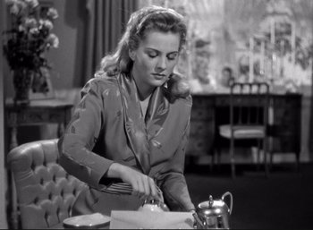 Movie still from “Suspicion” (1941), directed by Alfred Hitchcock – A black and white photo of a woman cutting a cake; Medium shot, Low angle