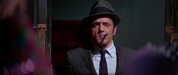 Movie still from “Sweet Charity” (1969), directed by Bob Fosse – A man in a suit and hat smoking a cigarette; Close Up shot, Low angle