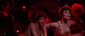 Movie still from “Sweet Charity” (1969), directed by Bob Fosse – A woman in a gold dress is sitting on the ground; Medium shot, Low angle