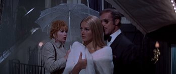 Movie still from “Sweet Charity” (1969), directed by Bob Fosse – A group of people standing under an open umbrella; Medium shot, Over the shoulder angle