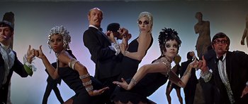 Movie still from “Sweet Charity” (1969), directed by Bob Fosse – A group of people dressed up in costumes; Medium shot, Low angle