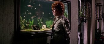 Movie still from “Sweet Charity” (1969), directed by Bob Fosse – A woman standing in front of a fish tank; Medium shot, Over the shoulder angle