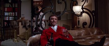 Movie still from “Sweet Charity” (1969), directed by Bob Fosse – A man sitting on a couch holding a wine glass and a bottle; Medium shot, Low angle