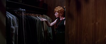 Movie still from “Sweet Charity” (1969), directed by Bob Fosse – A woman in a black dress looking at clothes on hangers; Medium shot, High angle
