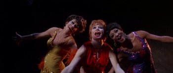 Movie still from “Sweet Charity” (1969), directed by Bob Fosse – A group of three women standing next to each other on a stage; Medium shot, Low angle