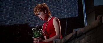 Movie still from “Sweet Charity” (1969), directed by Bob Fosse – A woman in a red dress holding a bouquet of flowers; Medium shot, Low angle