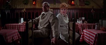 Movie still from “Sweet Charity” (1969), directed by Bob Fosse – An older man and a younger woman holding hands in front of a fence; Medium shot, Low angle