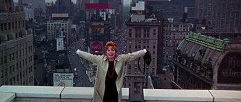 Movie still from “Sweet Charity” (1969), directed by Bob Fosse – A woman standing on the roof of a building with her arms outstretched; Wide shot, Low angle