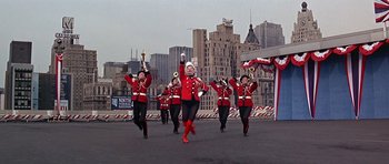 Movie still from “Sweet Charity” (1969), directed by Bob Fosse – A group of people in red uniforms marching in a parade; Wide shot, Low angle