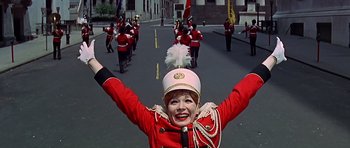 Movie still from “Sweet Charity” (1969), directed by Bob Fosse – A woman in a marching band uniform with her hands in the air; Medium shot, Low angle