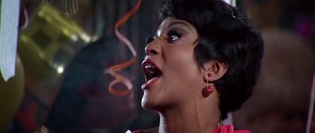 Movie still from “Sweet Charity” (1969), directed by Bob Fosse – A woman with her mouth wide open with a red earring hanging from the side of her mouth; Close Up shot, Low angle