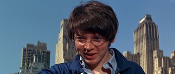 Movie still from “Sweet Charity” (1969), directed by Bob Fosse – A person with glasses is smiling for the camera; Close Up shot, Low angle