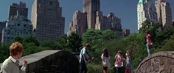 Movie still from “Sweet Charity” (1969), directed by Bob Fosse – A group of people walking in a park near tall buildings; Wide shot, Low angle