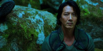Movie still from “Altered Carbon” (2018), created by Laeta Kalogridis – A man in a green shirt is standing in front of a rock; Close Up shot, High angle