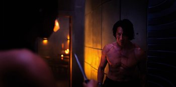 Movie still from “Altered Carbon” (2018), created by Laeta Kalogridis – A shirtless man holding a knife in front of a mirror; Medium shot, Over the shoulder angle