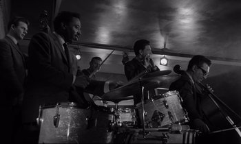 Movie still from “Sweet Smell of Success” (1957), directed by Alexander Mackendrick – A black and white photo of a group of men playing drums; Medium shot, Low angle