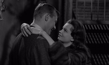 Movie still from “Sweet Smell of Success” (1957), directed by Alexander Mackendrick – A man and a woman embracing each other in front of a brick wall; Close Up shot, Over the shoulder angle