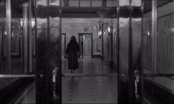 Movie still from “Sweet Smell of Success” (1957), directed by Alexander Mackendrick – A woman in a long coat walking down a hall way; Extreme Wide shot, Over the shoulder angle