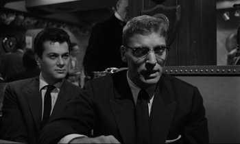 Movie still from “Sweet Smell of Success” (1957), directed by Alexander Mackendrick – A man in a suit sitting next to another man in a suit; Close Up shot, Low angle