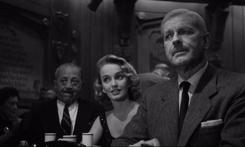 Movie still from “Sweet Smell of Success” (1957), directed by Alexander Mackendrick – A black - and - white photo of a man and a woman and an older man; Medium shot, Low angle