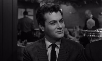 Movie still from “Sweet Smell of Success” (1957), directed by Alexander Mackendrick – Black and white photograph of a man wearing a suit and tie; Close Up shot, Over the shoulder angle