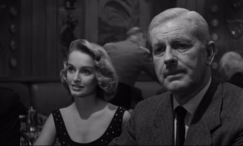 Movie still from “Sweet Smell of Success” (1957), directed by Alexander Mackendrick – An older man and a younger woman are posing for a picture; Close Up shot, Over the shoulder angle