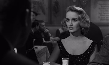 Movie still from “Sweet Smell of Success” (1957), directed by Alexander Mackendrick – A black and white photo of a woman sitting at a table; Close Up shot, Over the shoulder angle