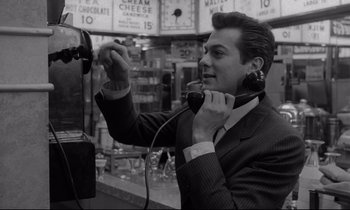 Movie still from “Sweet Smell of Success” (1957), directed by Alexander Mackendrick – A black and white photo of a man talking on a pay phone; Close Up shot, Low angle