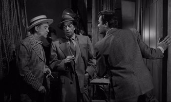 Movie still from “Sweet Smell of Success” (1957), directed by Alexander Mackendrick – A group of men standing next to each other in a room; Medium shot, Over the shoulder angle