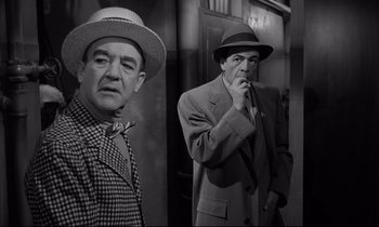 Movie still from “Sweet Smell of Success” (1957), directed by Alexander Mackendrick – A man in a hat and a man in a suit and tie; Medium shot, Low angle