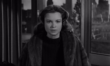 Movie still from “Sweet Smell of Success” (1957), directed by Alexander Mackendrick – A young woman wearing a fur coat in front of a window; Close Up shot, Over the shoulder angle