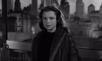 Movie still from “Sweet Smell of Success” (1957), directed by Alexander Mackendrick – A woman in a fur coat standing in front of a window; Close Up shot, Over the shoulder angle