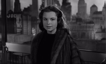 Movie still from “Sweet Smell of Success” (1957), directed by Alexander Mackendrick – A woman in a fur coat standing in front of a window; Medium shot, Over the shoulder angle