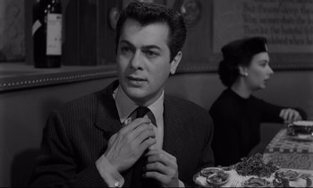 Movie still from “Sweet Smell of Success” (1957), directed by Alexander Mackendrick – A black and white photo of a man adjusting his neck tie; Close Up shot, Over the shoulder angle