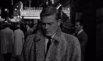 Movie still from “Sweet Smell of Success” (1957), directed by Alexander Mackendrick – A black and white photo of a man in a coat and tie; Close Up shot, High angle