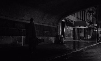 Movie still from “Sweet Smell of Success” (1957), directed by Alexander Mackendrick – A man walking down a street at night; Wide shot, High angle