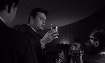 Movie still from “Sweet Smell of Success” (1957), directed by Alexander Mackendrick – A man holding a glass in front of another man holding a camera; Close Up shot, Low angle